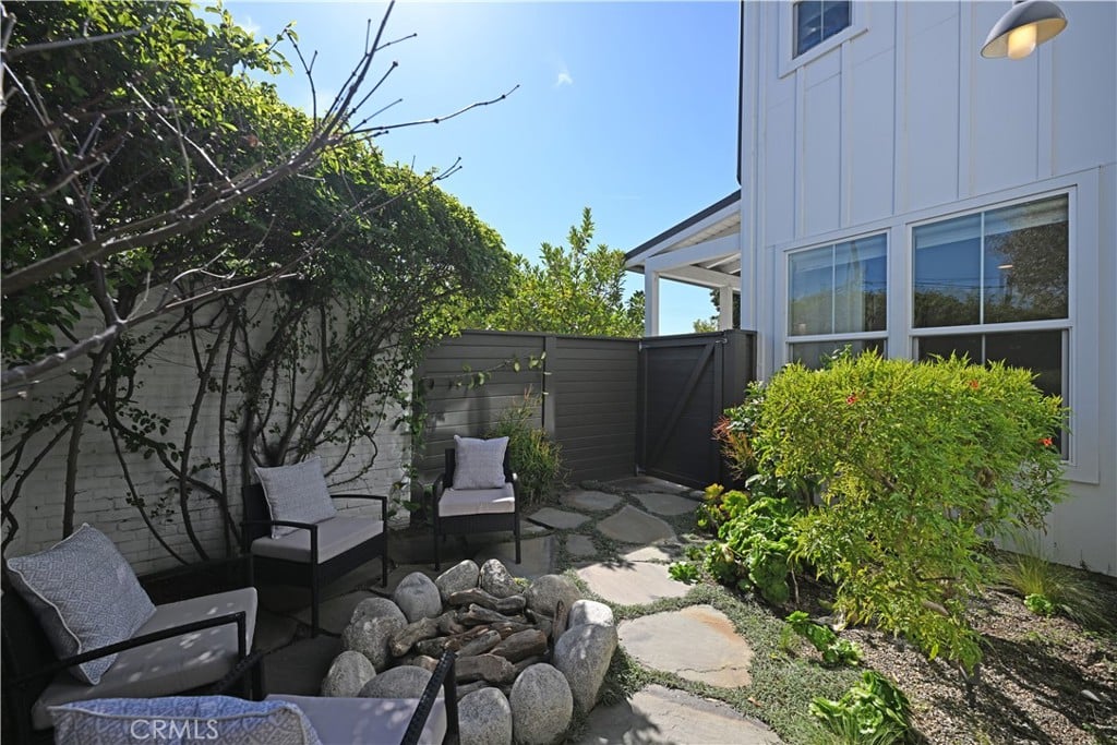 A walled side yard with chairs around a stone fire pit